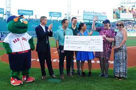 A group stands on the Red Sox baseball field presenting an oversized check to VCIL.